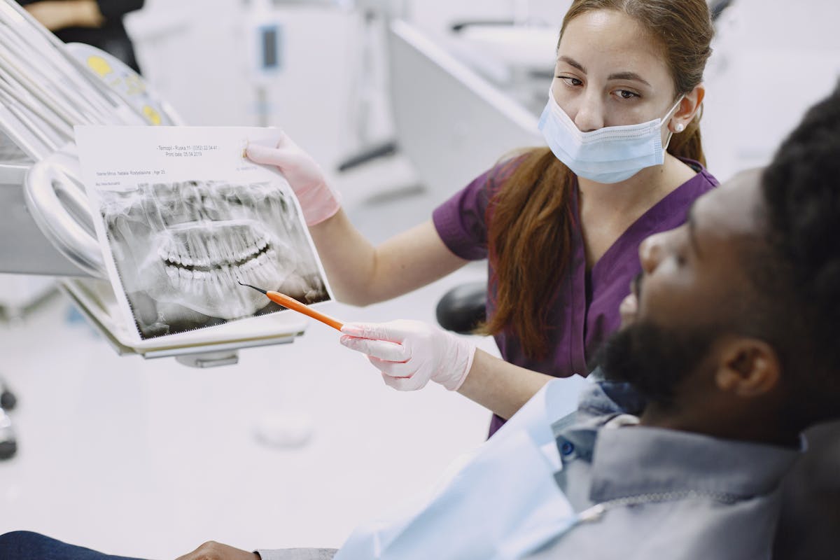 Dentist explaining an X-ray to a patient in a dental chair